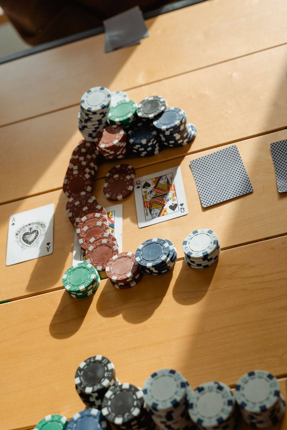 Chip dan kartu poker di atas meja kayu dengan cahaya alami